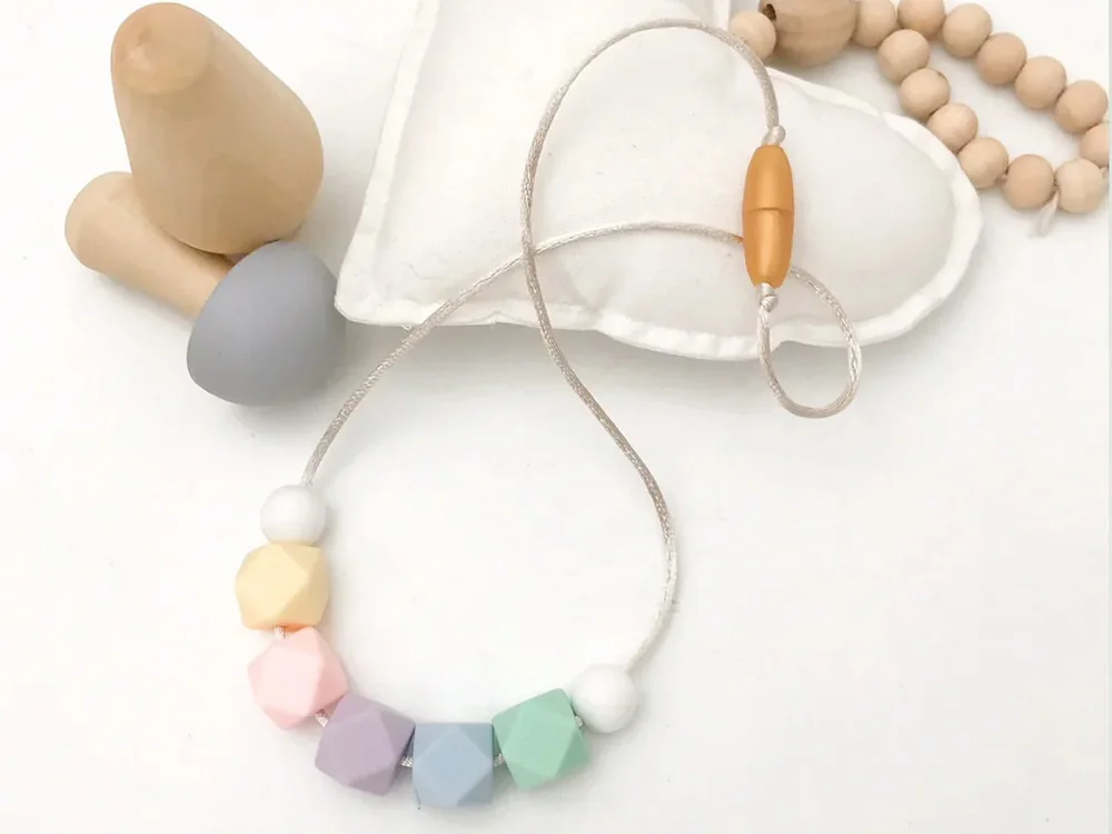 Pastel chewable sensory necklace styled with neutral accessories
